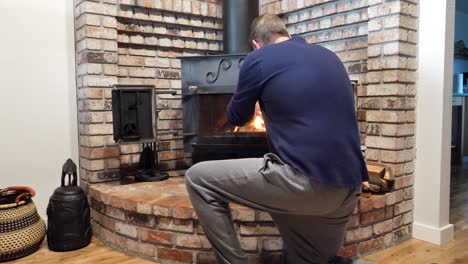 Male-warm-up-cold-hands-beside-fireplace-in-home-lounge