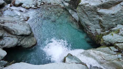 Pan-across-short-white-waterfall-into-blue-green-slot-canyon-pool