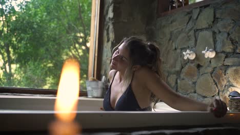 Young-attractive-female-having-a-fancy-bath-in-a-jacuzzi-with-big-green-nature-window-able-to-slow-motion-60fps-3