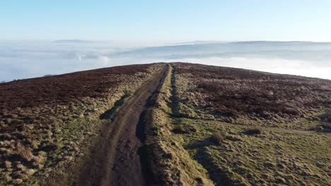Cloudy-misty-sunrise-valley-aerial-moorland-hiking-hillside-following-muddy-path-Lancashire