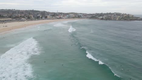 Spritzende-Wellen-Mit-Touristen-In-Bondi-Beach-Mit-Stadtlandschaft-Im-Hintergrund-In-Den-östlichen-Vororten,-Sydney,-New-South-Wales,-Australien