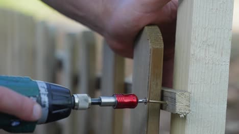 Building-a-fence,-close-up-of-drilling-in-the-final-screw-on-a-wooden-fence