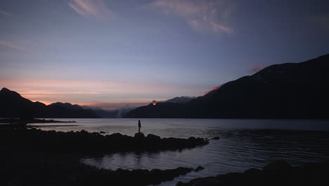 Person-releases-single-paper-lantern-into-night-sky-over-mountain-lake