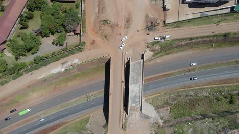 Aerial-view-above-a-highway-road-bridge,-with-vehicles-speeding-by,-in-Nairobi,-Kenya