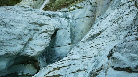 Wetsuit-man-jumps-from-rocky-ledge-into-limestone-slot-canyon-pool
