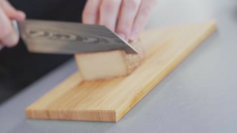 Sharp-knife-cutting-a-slice-off-a-smoked-Tofu-block