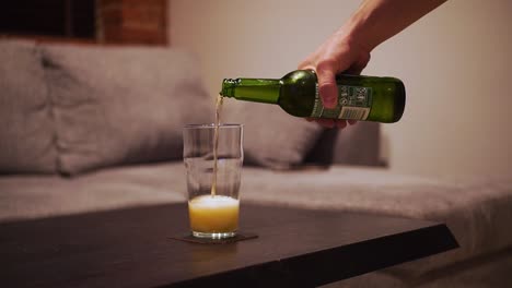 Die-Hand-Des-Mannes-Nimmt-Eine-Flasche-Bier-Und-Gießt-Sie-In-Ein-Glas,-Nahaufnahme