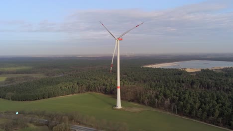 Aerial-pull-back,-single-three-blade-large-wind-turbine-in-Germany-near-Roads