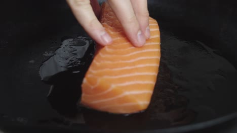 Chef-places-salmon-slice-onto-hot-frying-pan