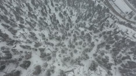 Birdseye-Aerial-View-of-Blizzard-Above-Steep-Snow-Capped-Hills-and-Rural-Roads