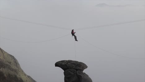 Rock-climber-on-a-zip-line-fixing-the-ropes-and-equipment