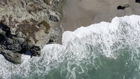 Top-down-view-over-ocean-waves-crashing-on-Big-Sur-coast,-California