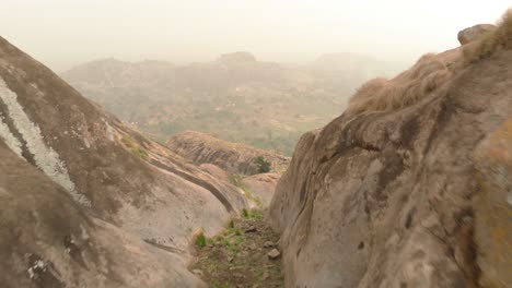 Aerial-shot-flying-over-a-African-man-in-a-valley-surrounded-by-granite-rocks