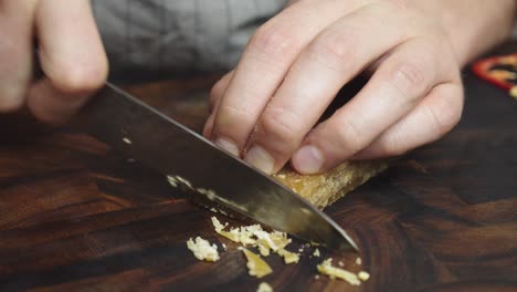 Slicing-brown-sugar-with-kitchen-knife-on-wooden-cut-board