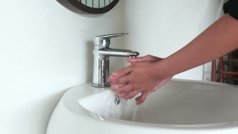 Waschen-Der-Hand-In-Einem-Waschbecken,-Um-Die-Haut-Zu-Waschen-Und-Wasser-Fließt-Durch-Die-Hände