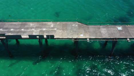 Old-abandoned-rusty-pier-on-Australian-coast,-Catherine-Hill-Bay,-aerial-view