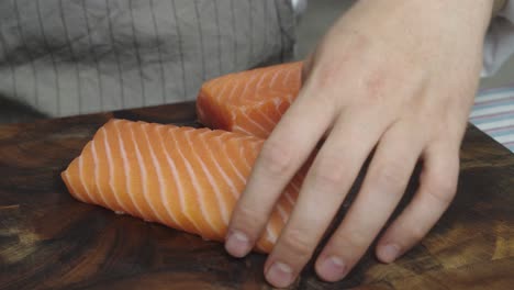 Cutting-salmon-into-three-slices-on-wooden-cut-board