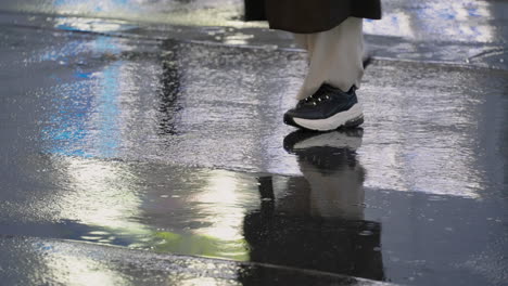 Gente-Cruzando-Una-Carretera-De-Hormigón-Húmedo-Durante-La-Tarde-Lluviosa-En-Tokio,-Japón