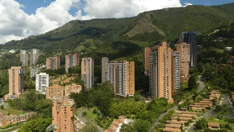 Drone-Descending-in-El-Poblado-Neighborhood-of-Medellin,-Colombia-with-Clear-View-of-Green-Andes-Mountains