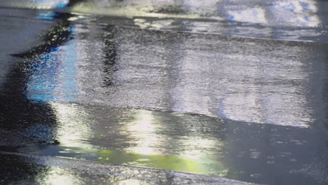Silhouettenreflexion-Auf-Regenpfützen-Einer-Person,-Die-über-Die-Asphaltstraße-In-Tokio,-Japan,-Geht