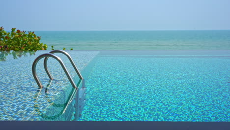 Empty-infinity-pool,-steps,-blue-water-and-amazing-view-of-tropical-sea-horizon,-slow-motion-full-frame