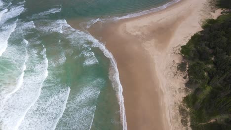 Weiße-Wellen-Rollen-Mit-üppiger-Vegetation-Am-Strand-Von-Sawtell-In-New-South-Wales,-Australien,-Ans-Ufer
