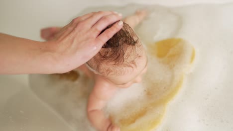Die-Hände-Der-Mutter-Reiben-Den-Kopf-Des-Babys-Mit-Shampoo