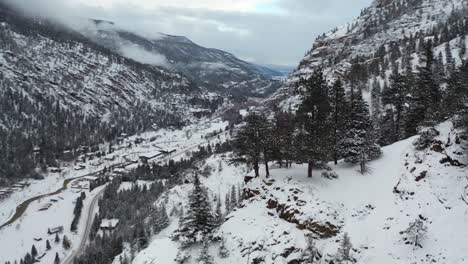 Aerial-view-of-steep-snow-capped-hills-and-mountain-winter-landscape-above-Ouray-town,-Colorado-USA,-dramatic-drone-shot