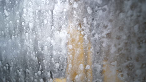 Close-up-of-window-being-cleaned-at-car-wash,-seen-from-inside-car