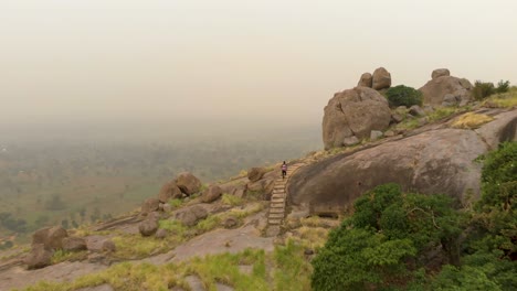 Aerial-shot-following-an-African-man-running-up-a-stair-case-on-a-granite-mountain-in-Africa