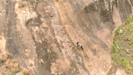 A-birds-eye-view-shot-of-an-African-man-rock-climbing-up-a-granite-rock-in-Africa
