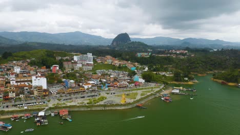 Backwards-Aerial-Flight-Reveals-Colorful-Town-of-Guatape-with-Piedra-del-Peñol-in-Background