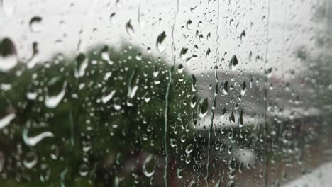 Close-up-of-rain-droplets-falling-down-on-window-glass-moisture-surface,-heavy-rain-shower-outside-condense-window