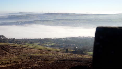 Industry-chimney-through-fog-mist-clouds-passing-countryside-valley-stone-battlement-viewpoint-left-reveal