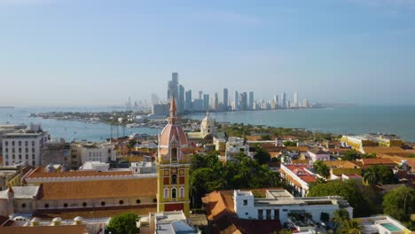 Drone-Flies-Over-Two-of-Cartagena's-Most-Historic-Churches,-Dolly-Shot-Toward-Cartagena-Skyline