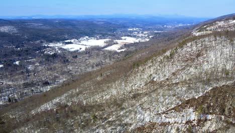 Aerial-drone-video-footage-of-a-snowy-mountain-valley-during-early-spring-with-sunny-blue-skies