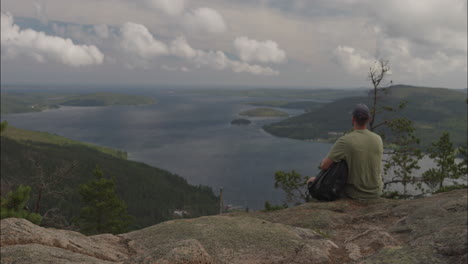 Establisher-shot-of-young-man-admiring-spectacular-Norway-landscape-on-viewpoint