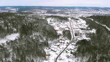 Forward-moving-aerial-over-countryside-road-amidst-human-settlement,-all-covered-under-snow