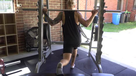 Tattoo-man-muscles-in-home-gym-back-leg-raise-smith-machine-lunge