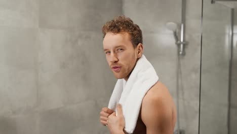 cute-sporty-man-with-white-towel-around-his-neck-tenses-his-biceps