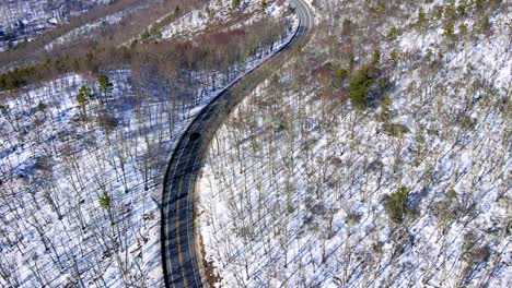 Aerial-upward-reveal-drone-video-footage-of-a-snowy,-blue-sky-mountain-valley-road-highway-through-the-mountains-in-the-Appalachians-on-the-Shawangunk-ridge,-in-new-York-state