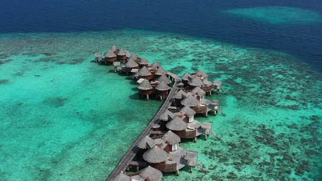 Luftaufnahme-Der-Wunderschönen-Malediven-Insel-über-Wasservilla-Bungalows-In-Der-Türkisfarbenen-Lagune-In-Der-Nähe-Des-Weißen-Sandstrandes-Am-Sonnigen-Tag-4k