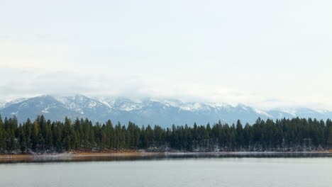 Timelapse-of-a-Beautiful,-Empty-Lake-with-Clouds-Passing-Over-the-Mountains-in-the-Background,-Negative-Space
