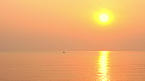 Ein-Kleines-Schiff-Schwimmt-In-Einem-Meer-Des-Sonnenuntergangs-Orange,-Rosa-Und-Gelber-Sonnenuntergang