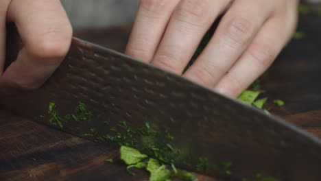 Cutting-herbs-ingredients-on-cut-board-with-big-kitchen-knife