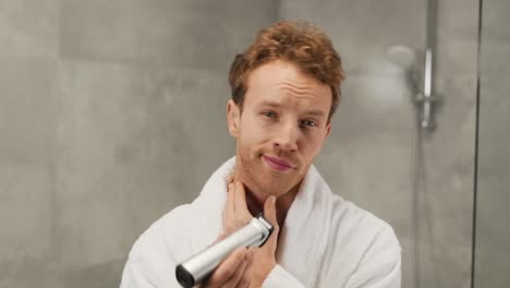 Portrait-of-a-handsome-man-trimming-his-beard-with-an-electric-clipper