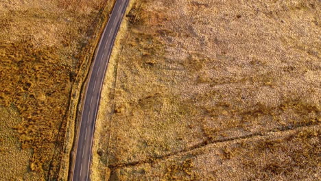 Aerial-flying-over-a-countryside-road,-landscape-shot-with-fields,-roads-and-cars-on-sunset