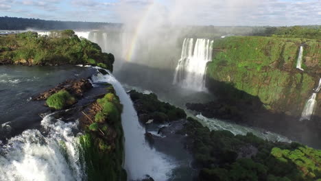 Aerial---A-rainbow-in-Iguazu-Falls,-Misiones,-Argentina,-wide-backward-shot