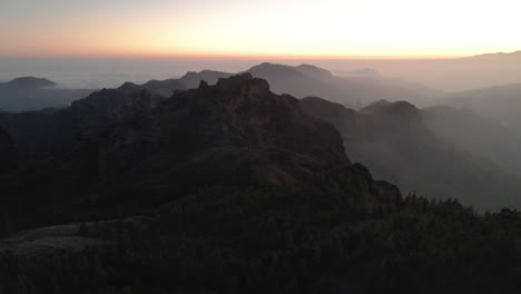 Erstaunliche-Filmische-Luftaufnahme-Eines-Atemberaubenden-Sonnenuntergangs-In-Den-Bergen-Von-Gran-Canaria-Mit-Einem-Nebel,-Der-über-Das-Land-Fegt
