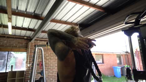 Tattoo-man-muscles-in-home-gym-doing-overhead-tricep-cable-pull